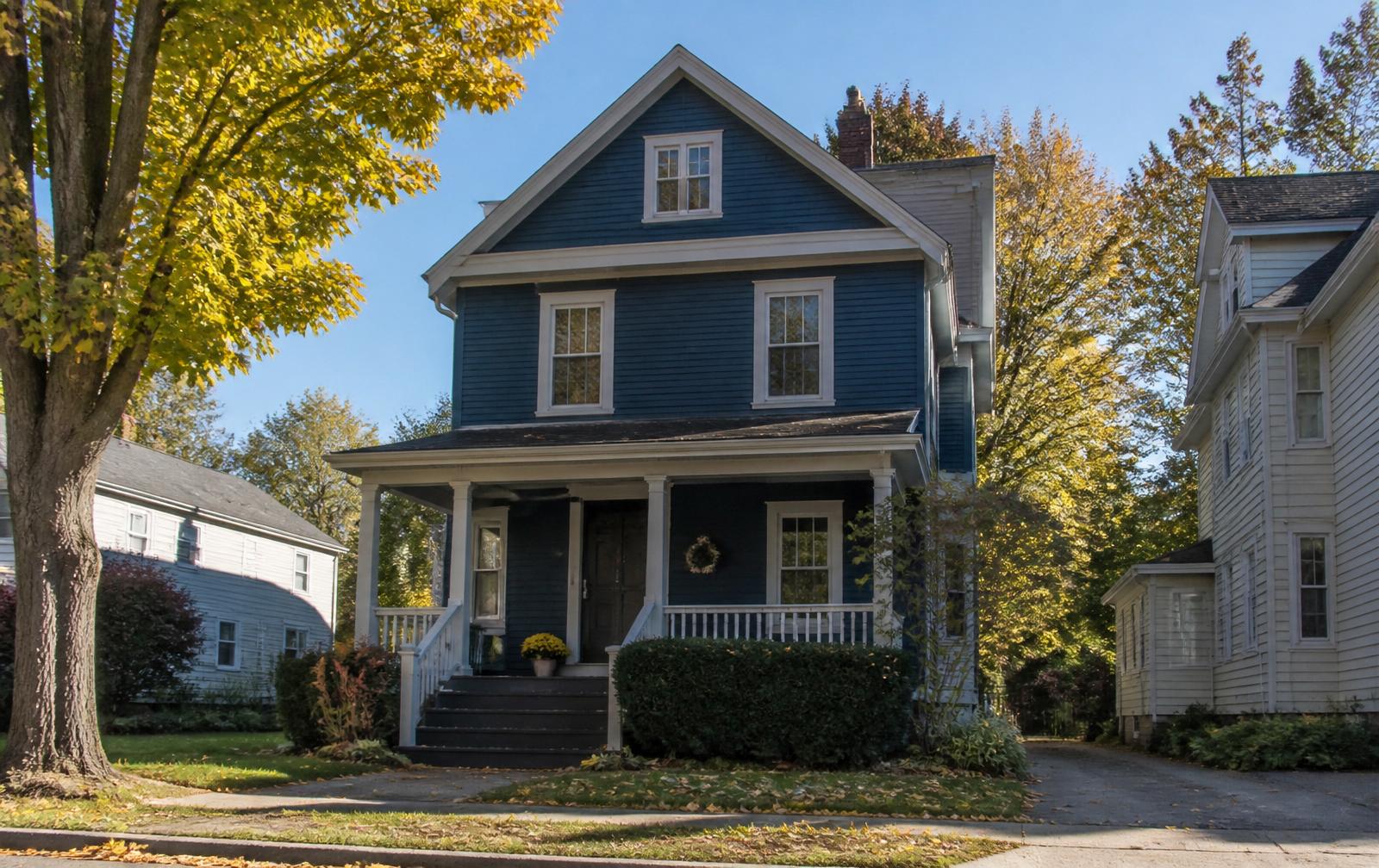 A classic Western New York two-story home with a covered front porch in autumn